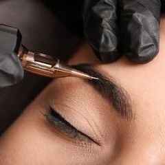 A woman is getting her eyebrows tattooed by a tattoo artist.