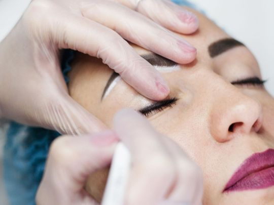 A woman is getting her eyeliner done in a beauty salon.