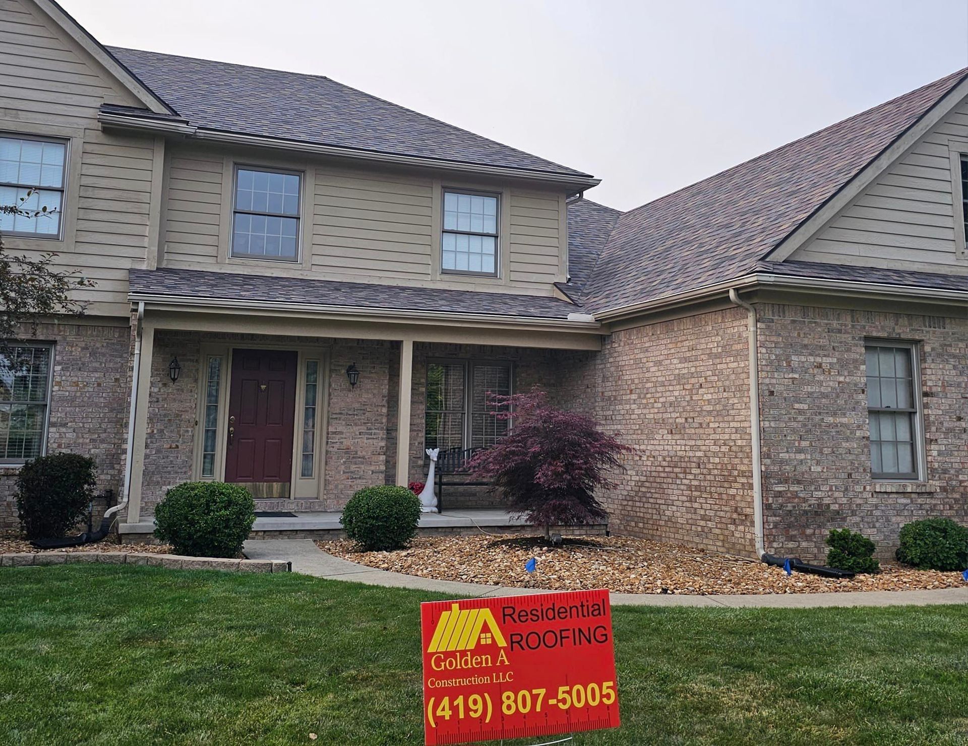 A large brick house with a red sign in front of it.