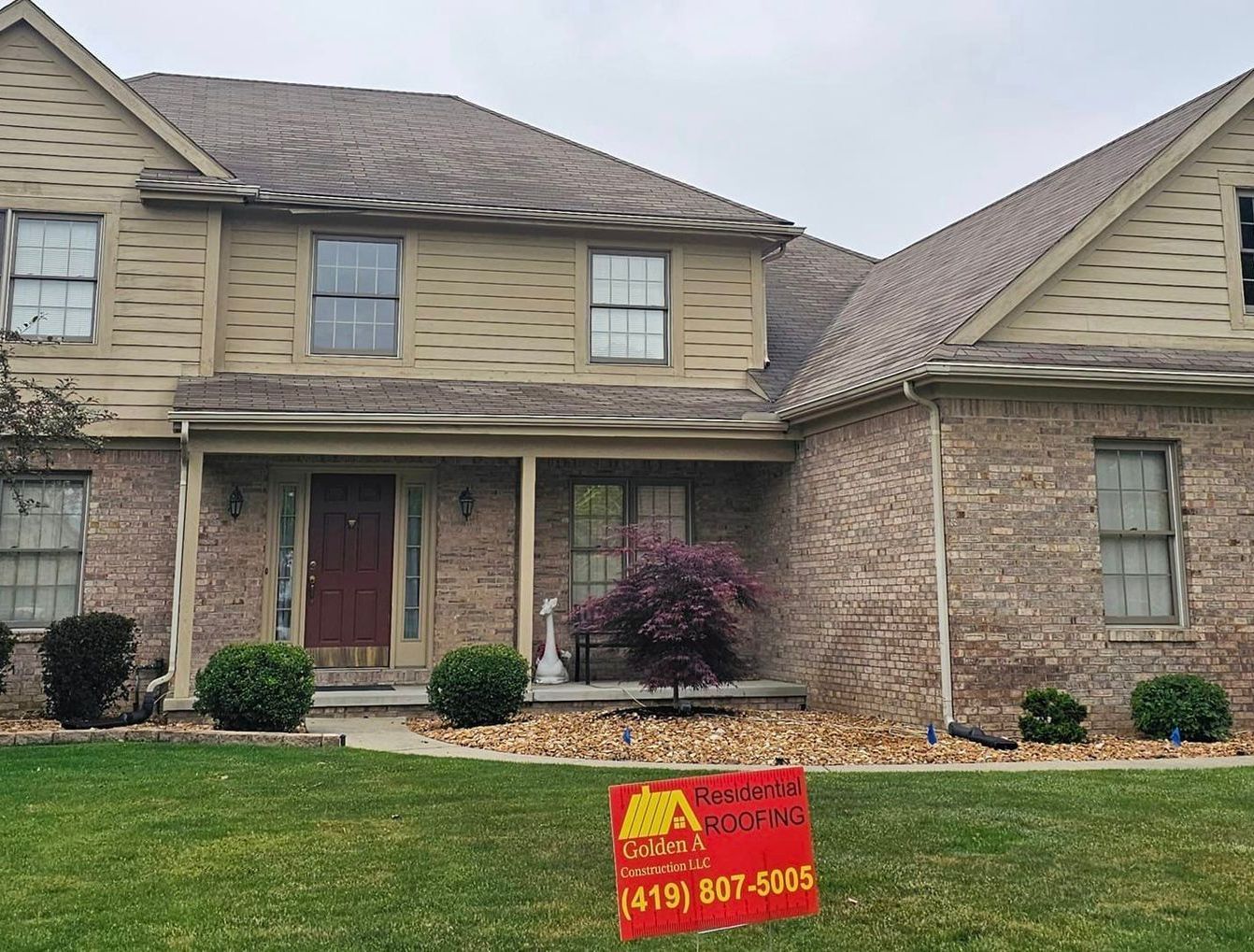 A large brick house with a red sign in front of it.