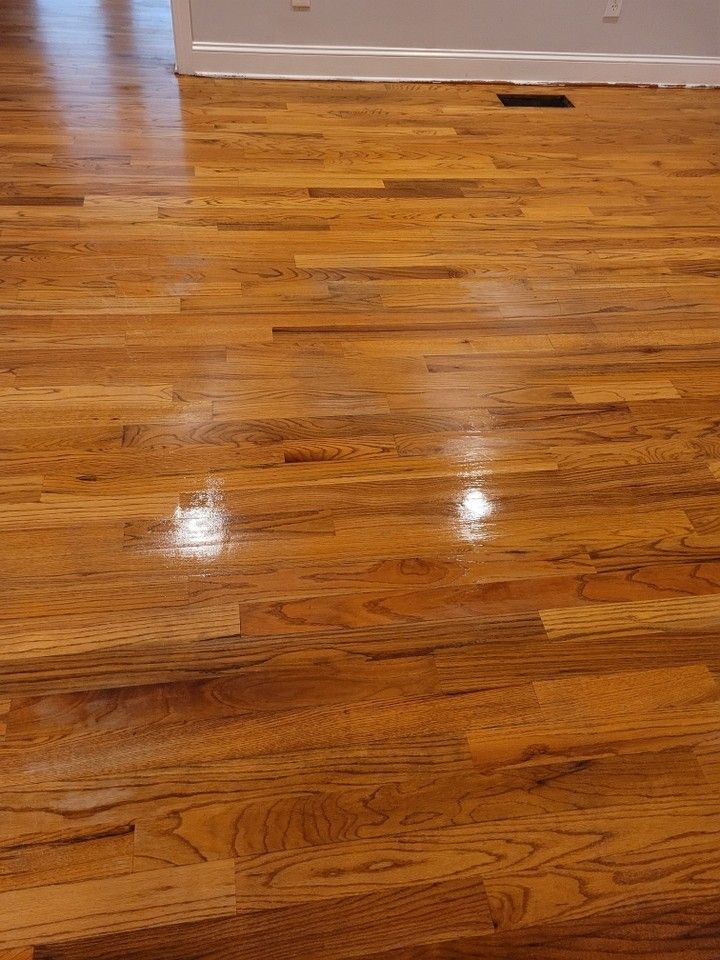 Close-up of hardwood floor, with golden brown planks reflecting light, next to a white wall.