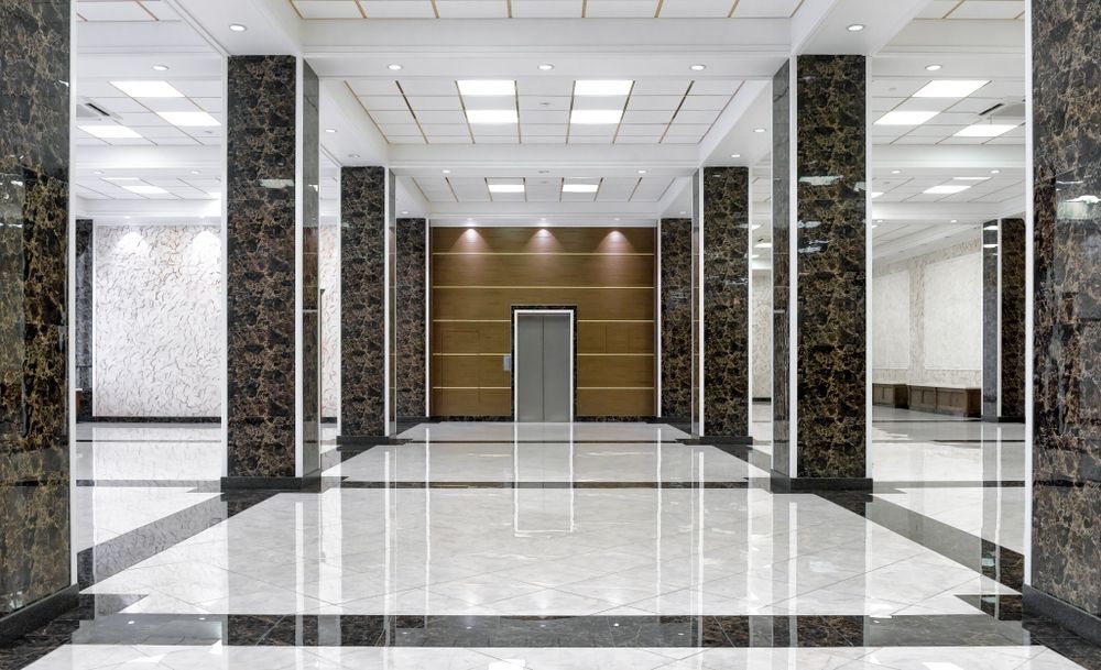 An elevator hall with marble columns, shiny floor, and elevator doors at the end.