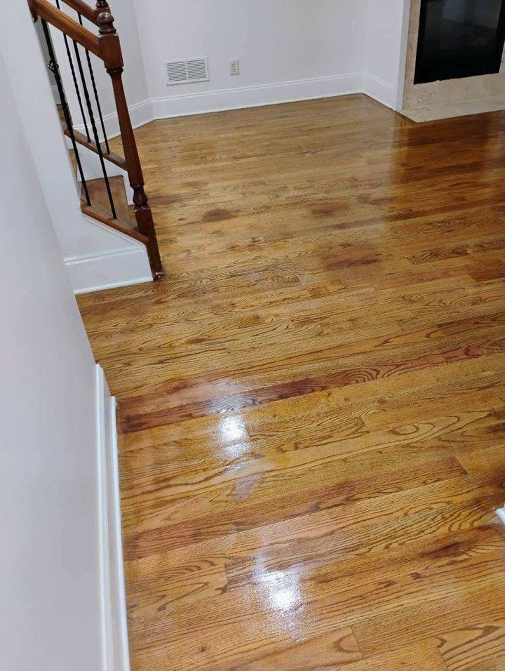 Hardwood floors in a room, with stairs and a fireplace visible; floors have water stains.