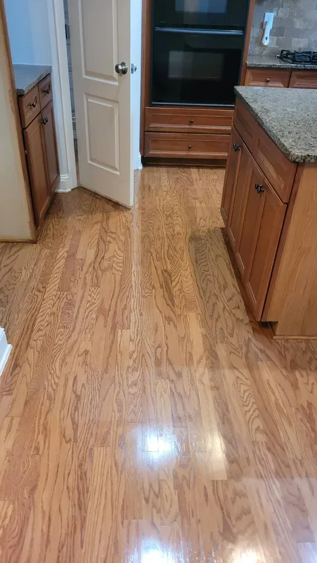 Wooden kitchen floor with cabinets, island, and oven. A white door is slightly open.