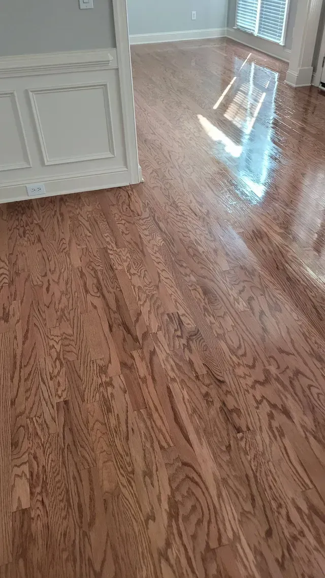 Hardwood floor with a glossy finish, reflecting light.