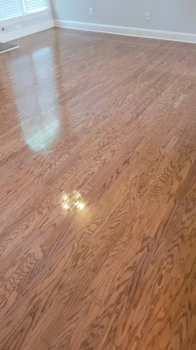Hardwood floor reflecting light from a window and a ceiling fixture.