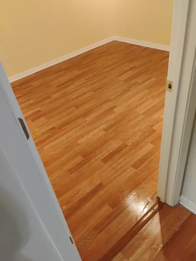 Light-colored hardwood floors in a room with yellow walls, viewed from a doorway.