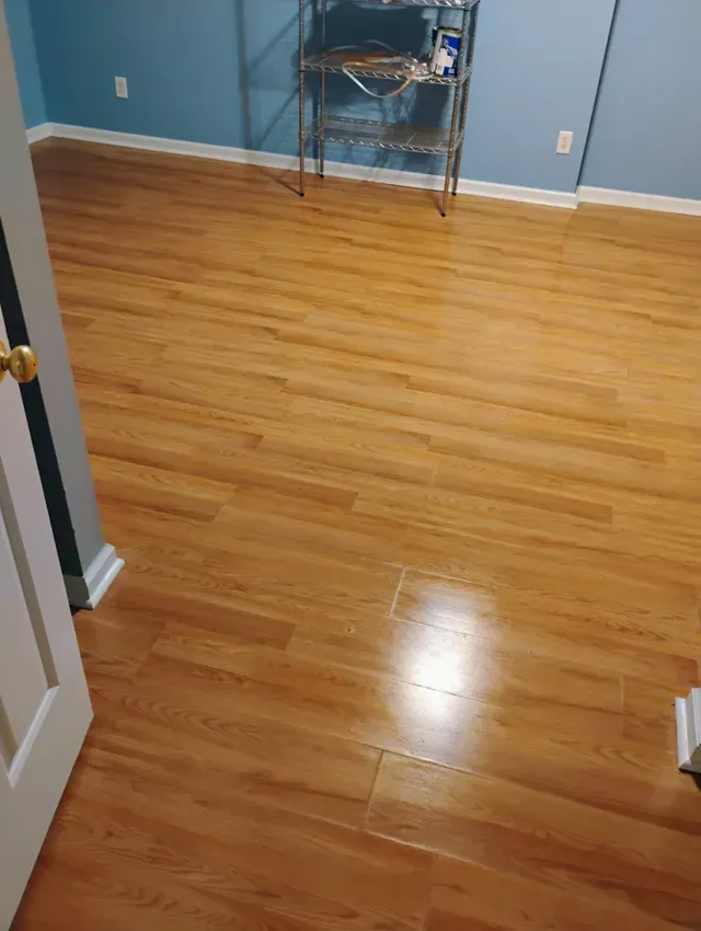 Wooden-look flooring in a room with blue walls. A metal shelf stands near the back wall.