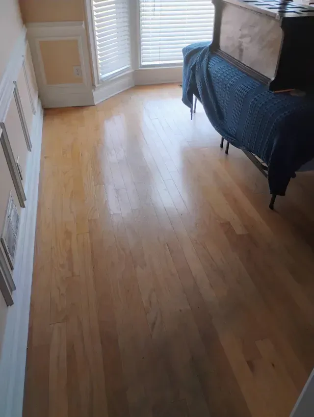 Hardwood floor in a room with windows and a covered table.
