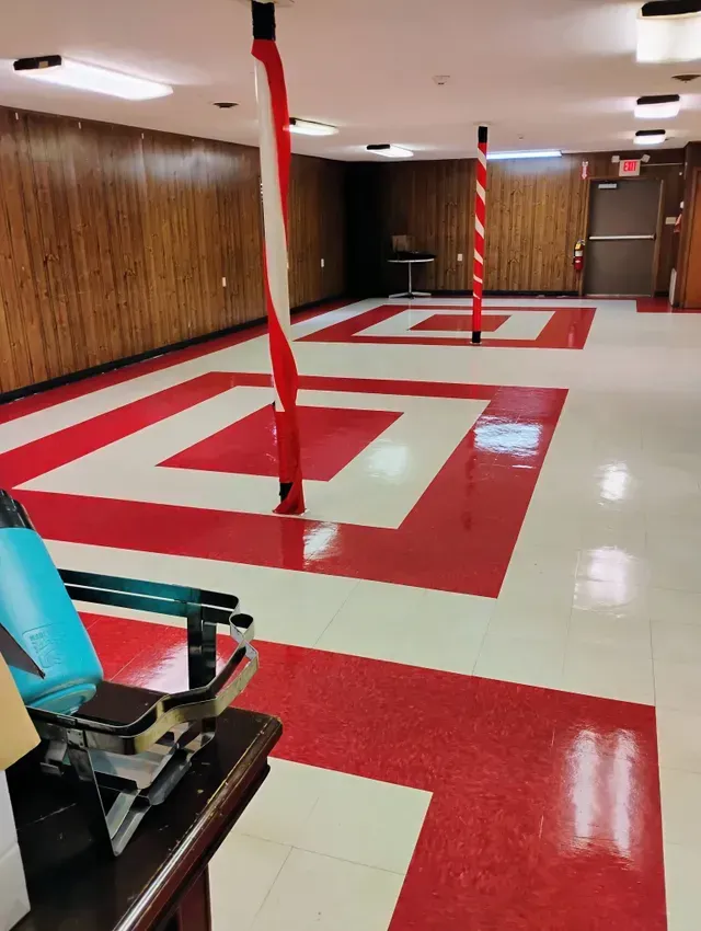 Red and white tiled floor with wood-paneled walls, two poles wrapped in red and white spiral, and a dental chair.
