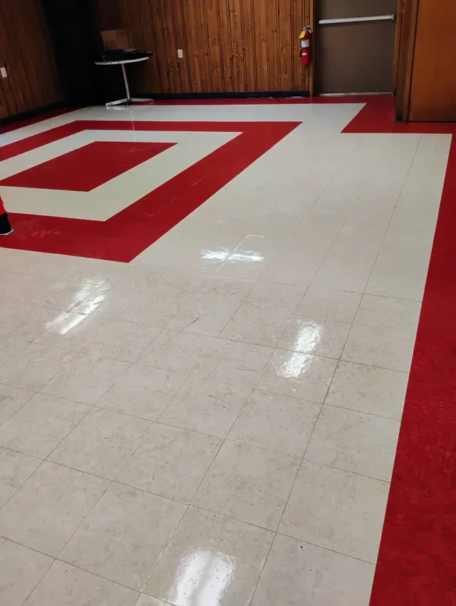 Red and white tiled floor in a room with wooden paneling and a fire extinguisher.