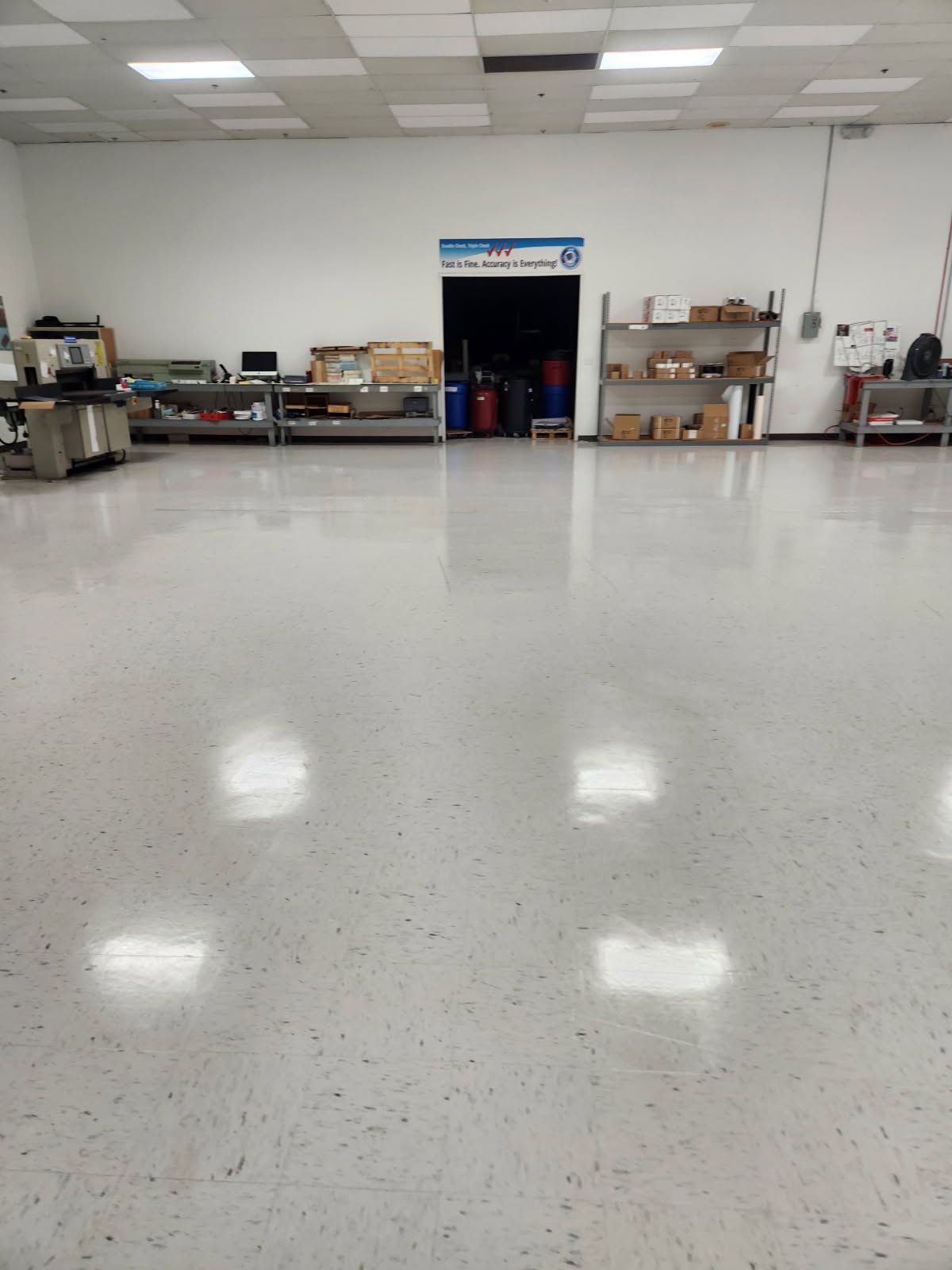 A bright, empty industrial space with a shiny, reflective floor. A doorway is centered in the background.