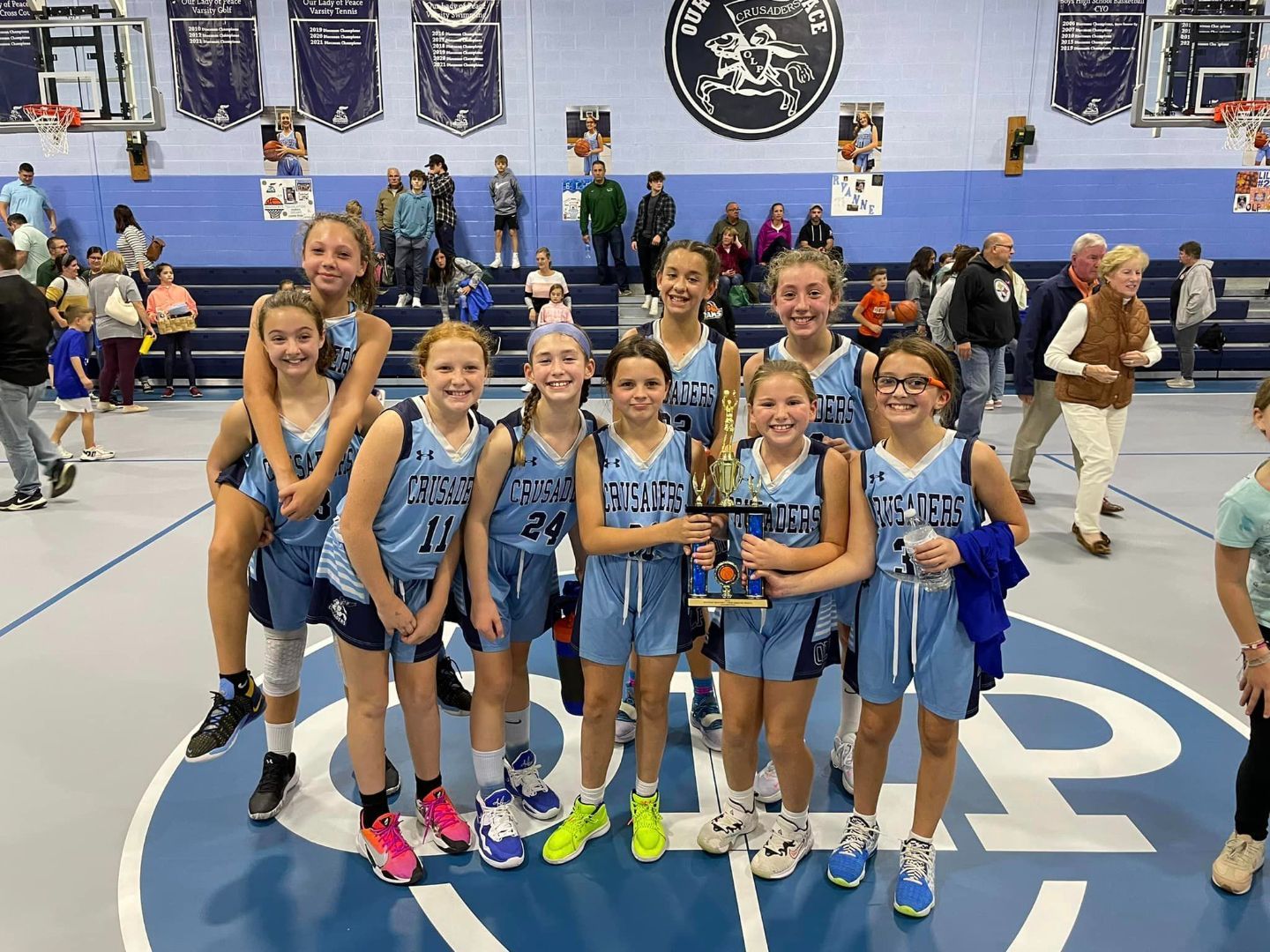 A group of young girls holding a trophy on a basketball court