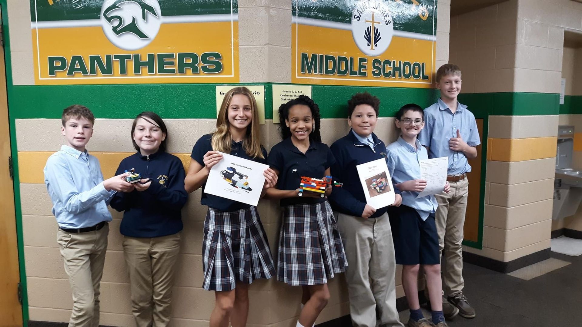 A group of children standing in front of a panthers middle school sign