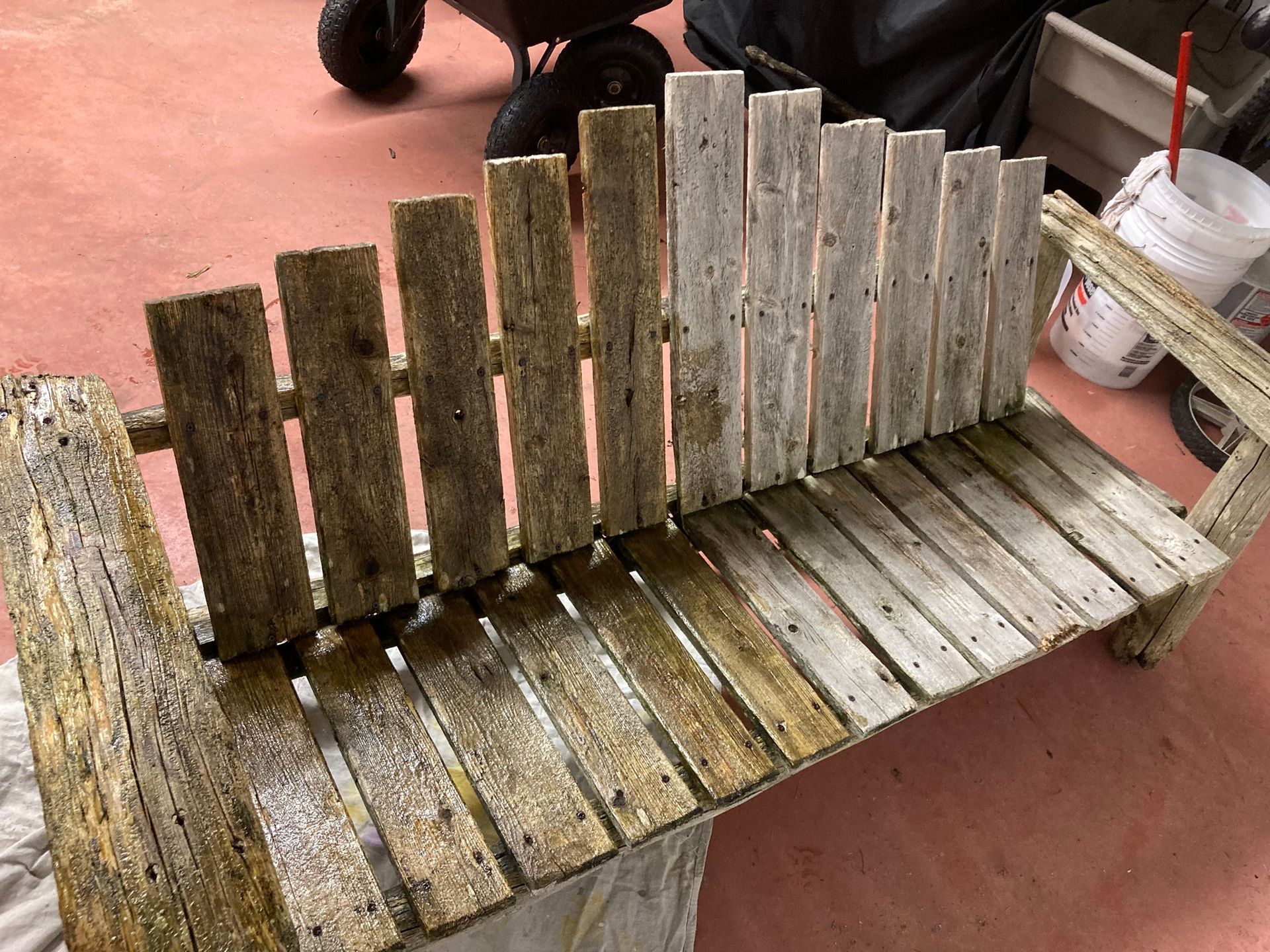 Wooden bench with weathered planks, partially treated, in a workshop setting.
