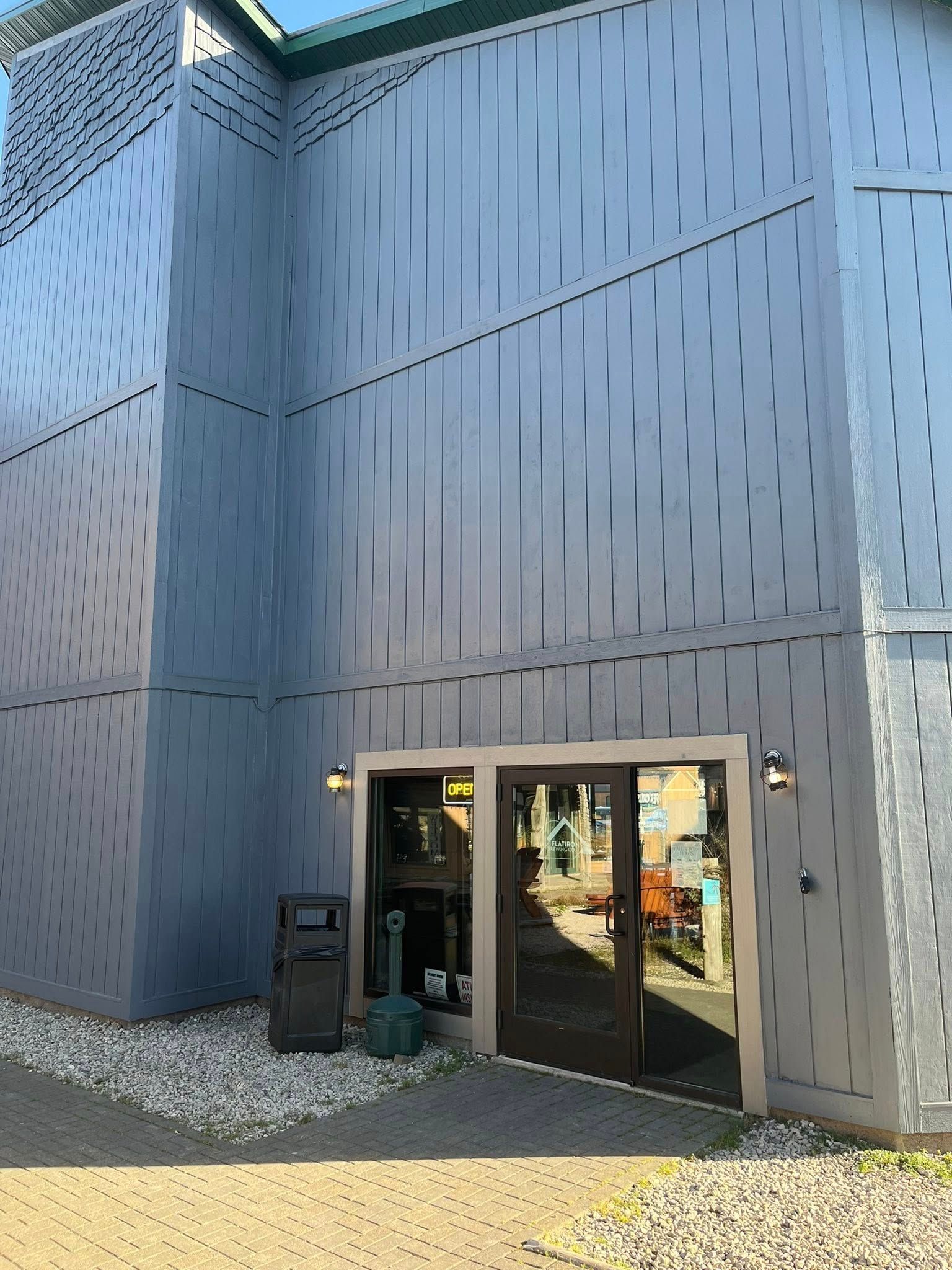 Building entrance with open doors. Gray exterior, pebbles at base.