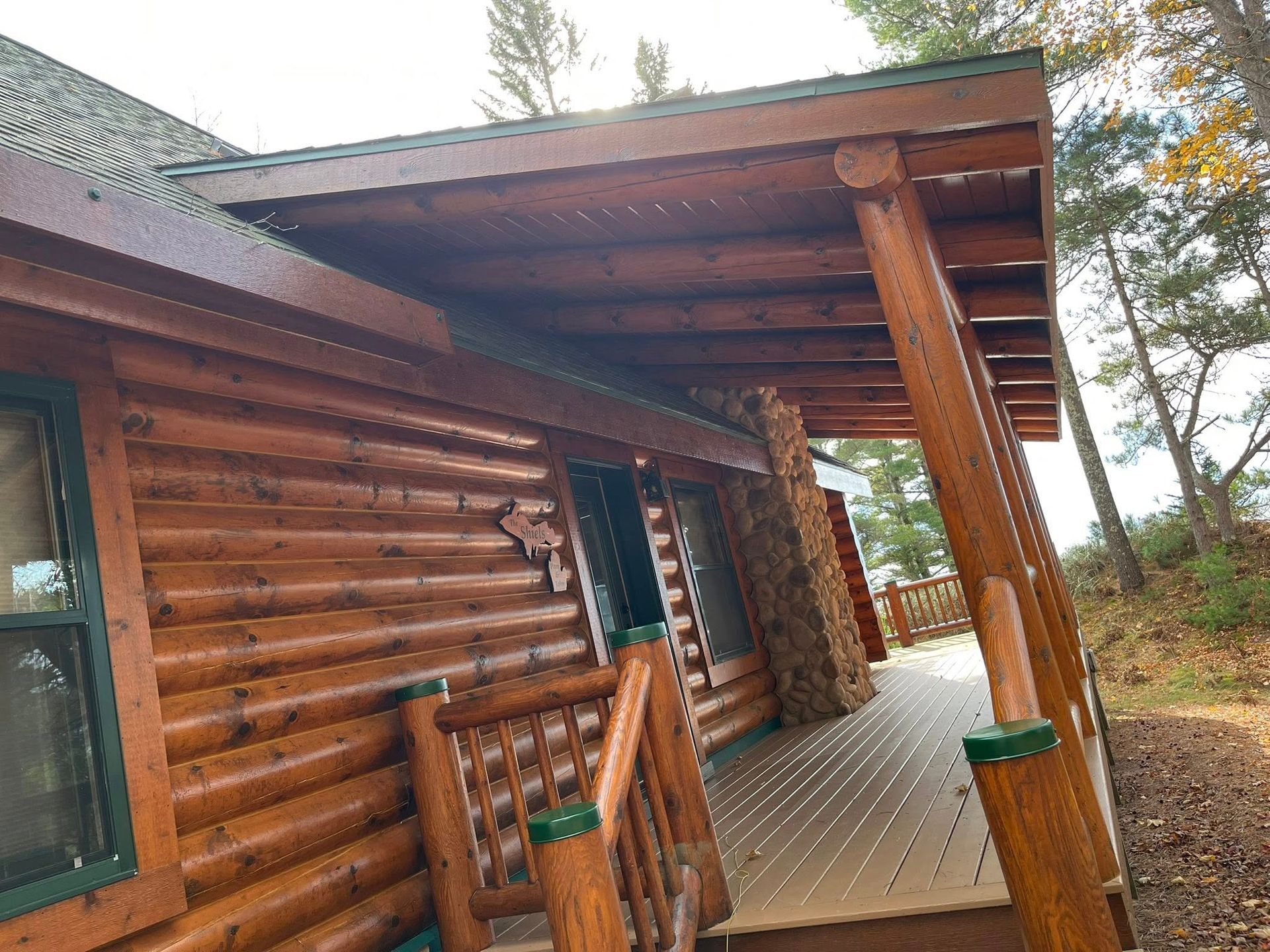 Wooden cabin with porch and steps, surrounded by trees.