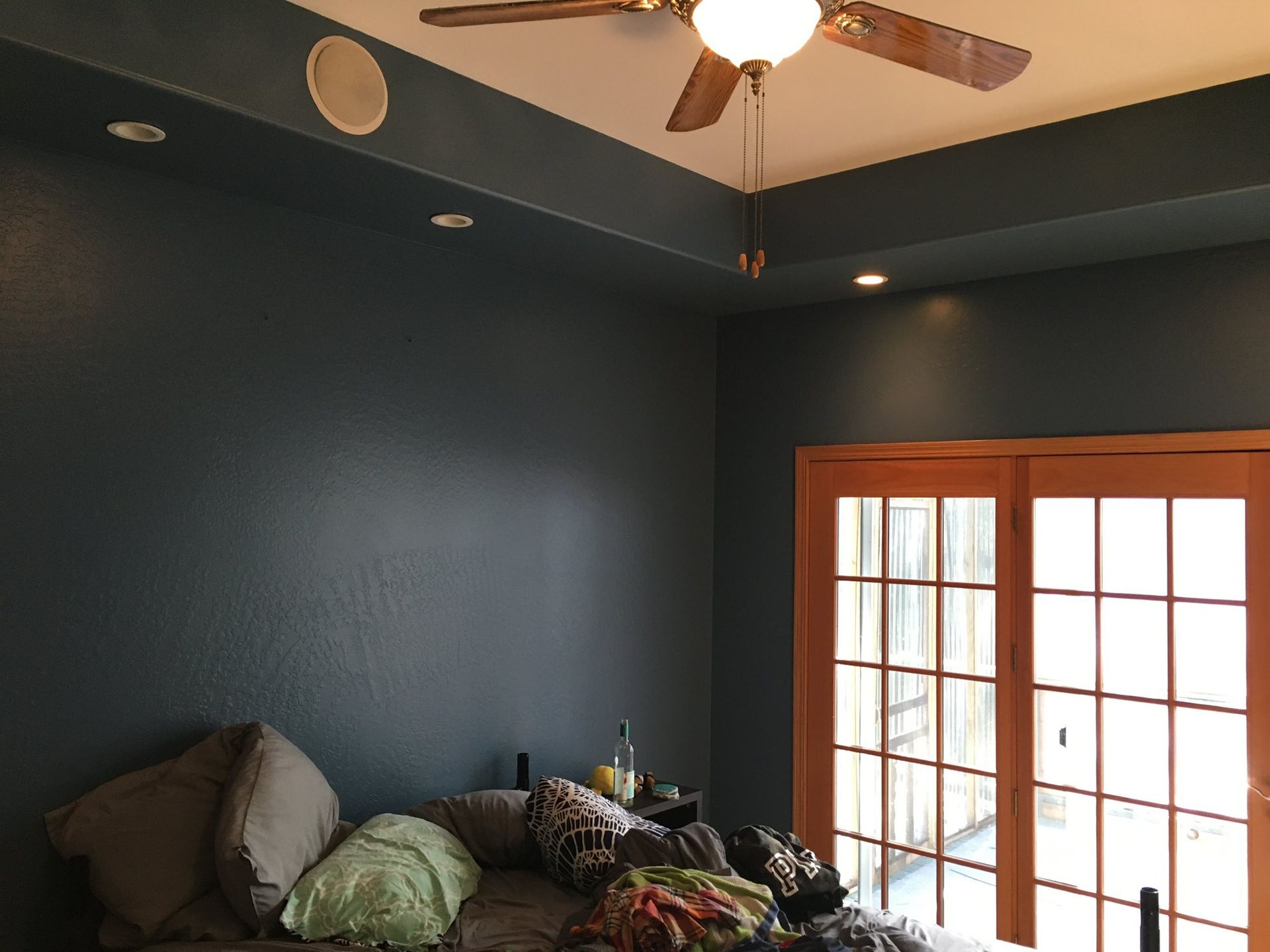 Dark blue bedroom with a bed, French doors, and a ceiling fan.