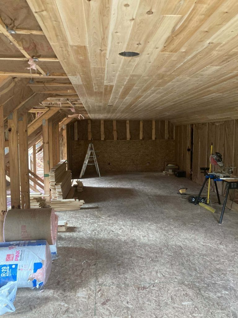 Interior of a room under construction with wood framing and a finished wood ceiling.