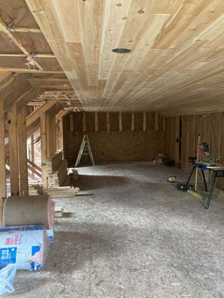 Interior of a room under construction with wood framing and a finished wood ceiling.