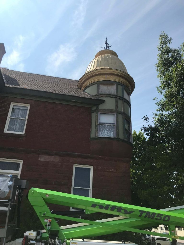 Brick house with a rounded tower; gold dome and weather vane. Green lift present.