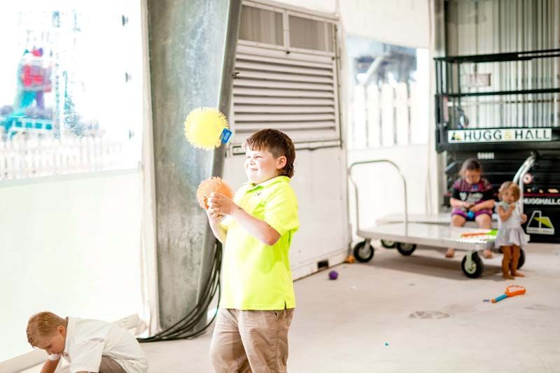 A boy in a yellow shirt is playing with a ball in a room.