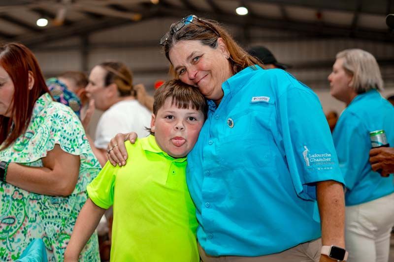 A woman in a blue shirt is posing for a picture with a boy in a neon green shirt.