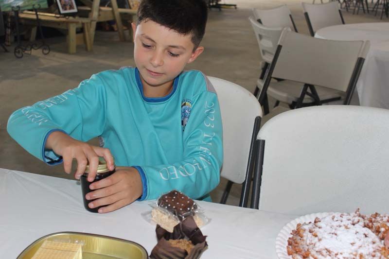 A young boy is sitting at a table with a plate of food.