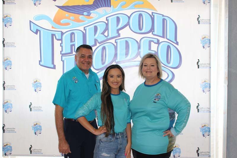 A group of people standing in front of a tarpon rodeo sign.