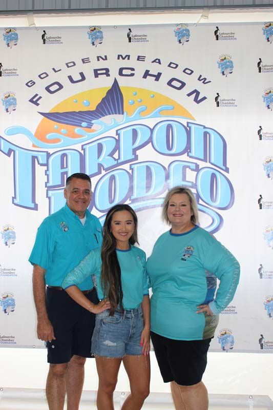A group of people standing in front of a tarpon rodeo sign.