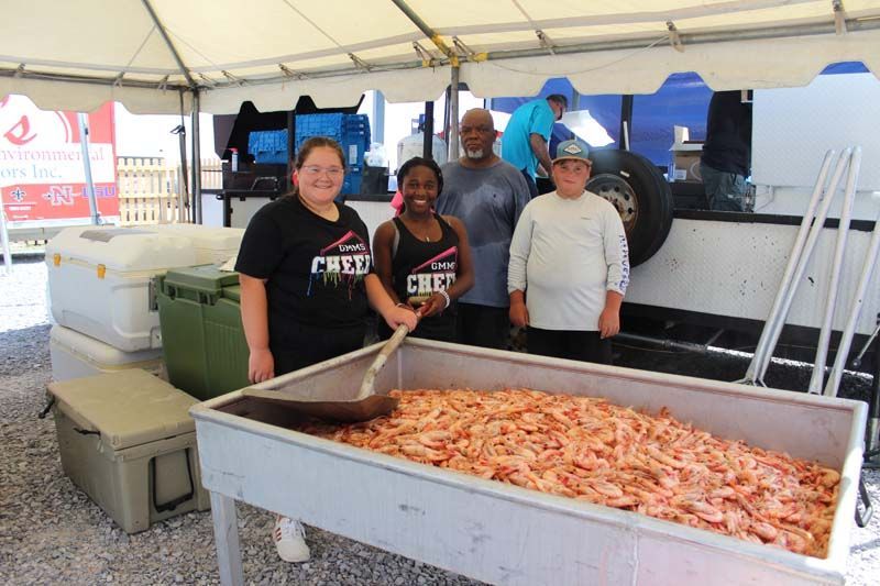 A group of people standing around a table filled with shrimp.