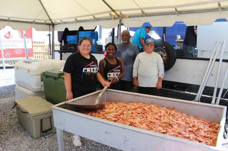 A group of people standing around a table filled with shrimp.