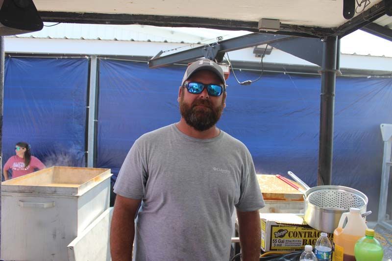 A man wearing sunglasses and a hat is standing in a kitchen.