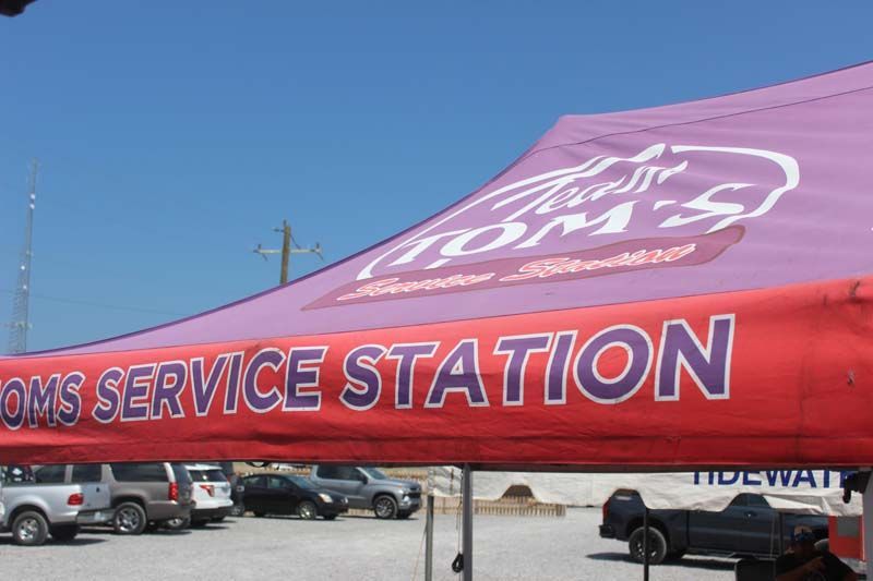 A red and purple tent that says tom 's service station
