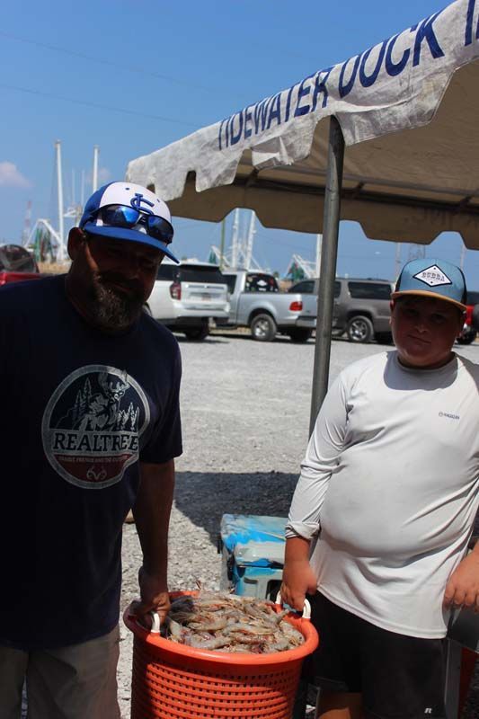 A man holding a basket of shrimp standing next to another man