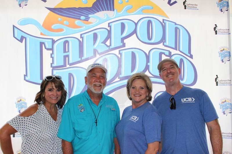 A group of people are posing for a picture in front of a tarpon dodo logo.