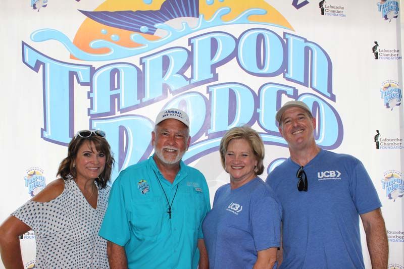 A group of people are posing for a picture in front of a tarpon dodge logo.