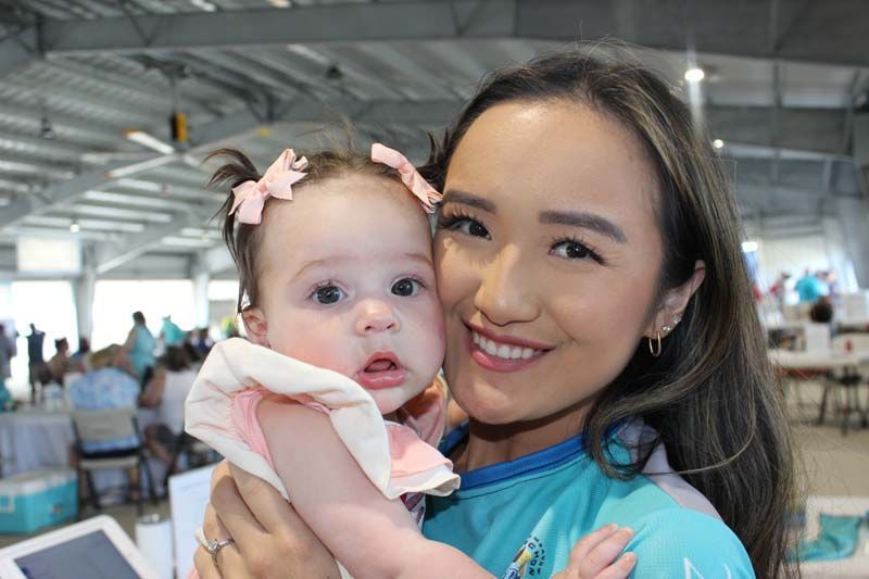 A woman is holding a baby in her arms and smiling.