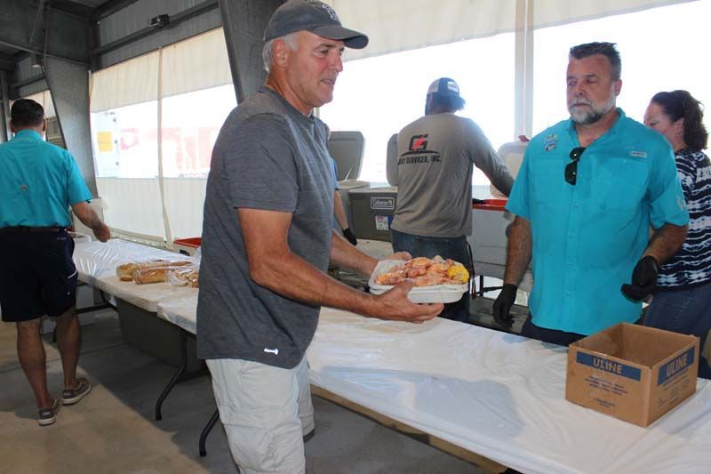 A man is holding a plate of food in front of a table.