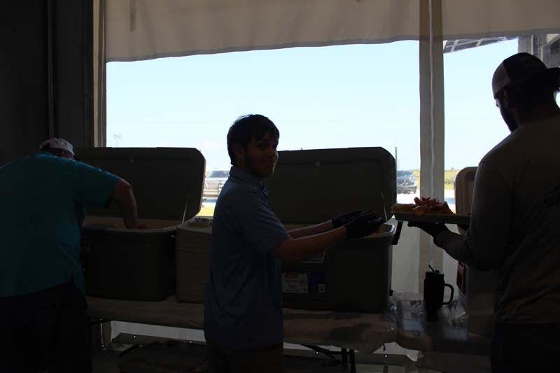 A group of people are standing around a table in front of a window.