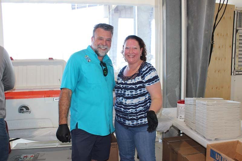 A man and a woman are posing for a picture in a kitchen.