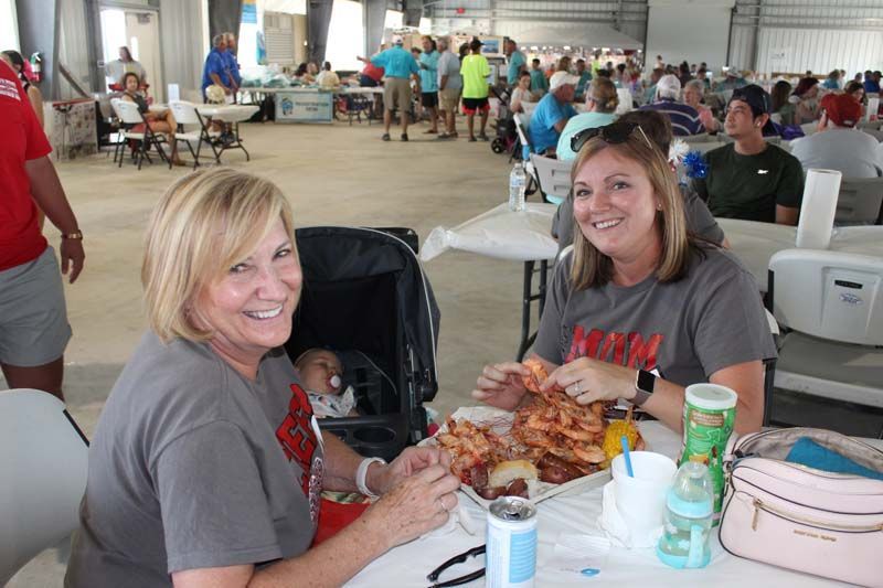 Two women are sitting at a table with a baby in a stroller.