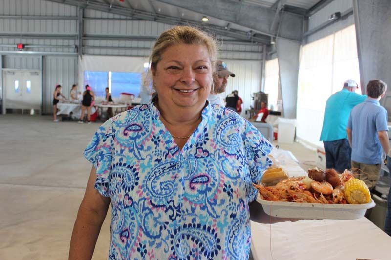 A woman is standing in front of a table with a tray of food.