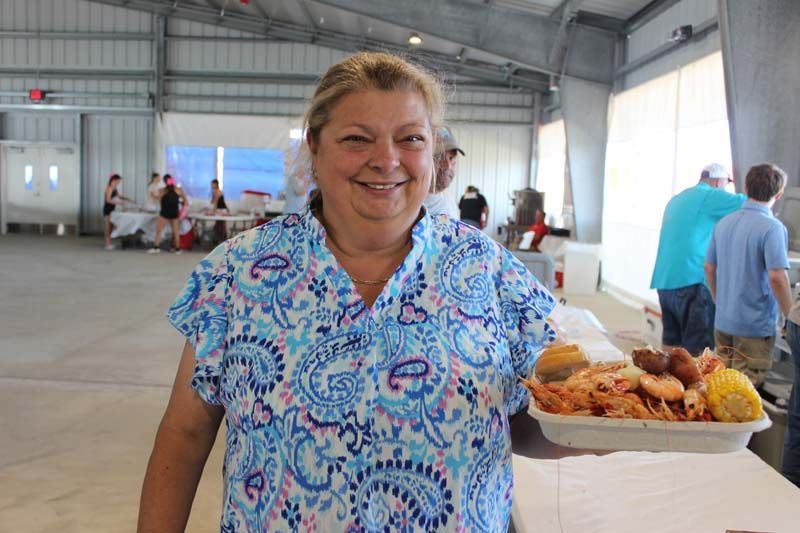 A woman is standing in front of a table with a tray of food.