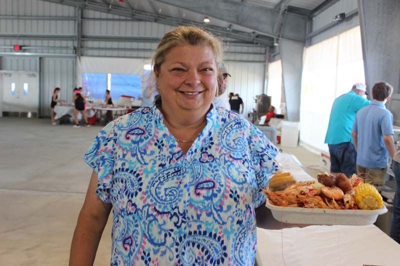 A woman is standing in front of a table with plates of food.