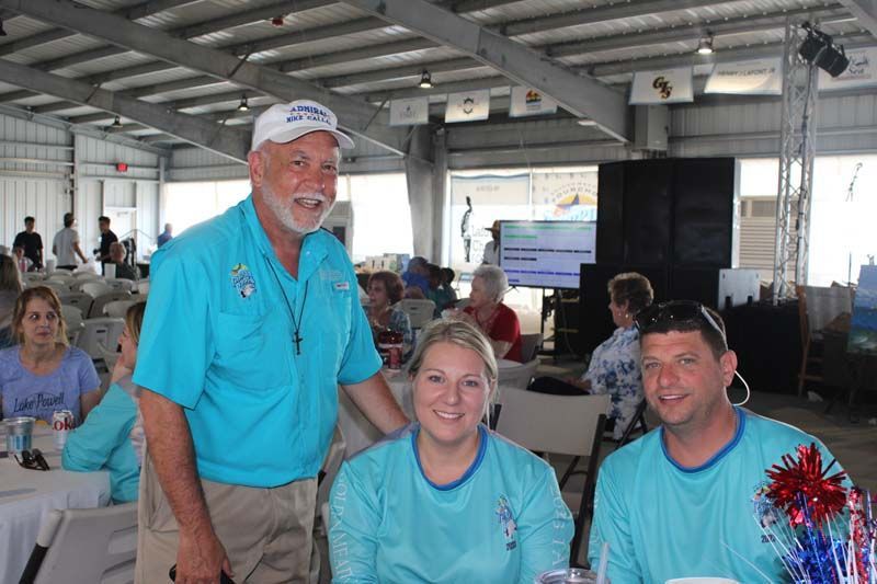 A man and two women are standing next to each other in a room.
