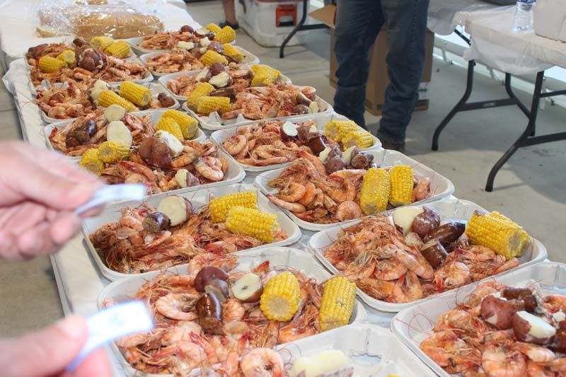 A table topped with plates of shrimp , corn and potatoes.
