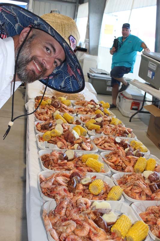 A man wearing a sombrero is standing in front of a long table filled with food.