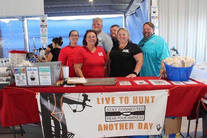 A group of people standing around a table with a sign that says live to hunt another day.