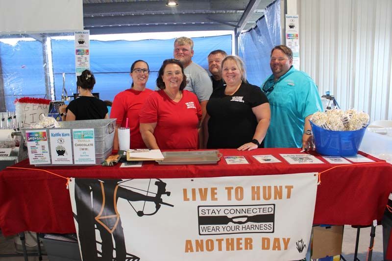 A group of people standing around a table with a sign that says live to hunt another day.